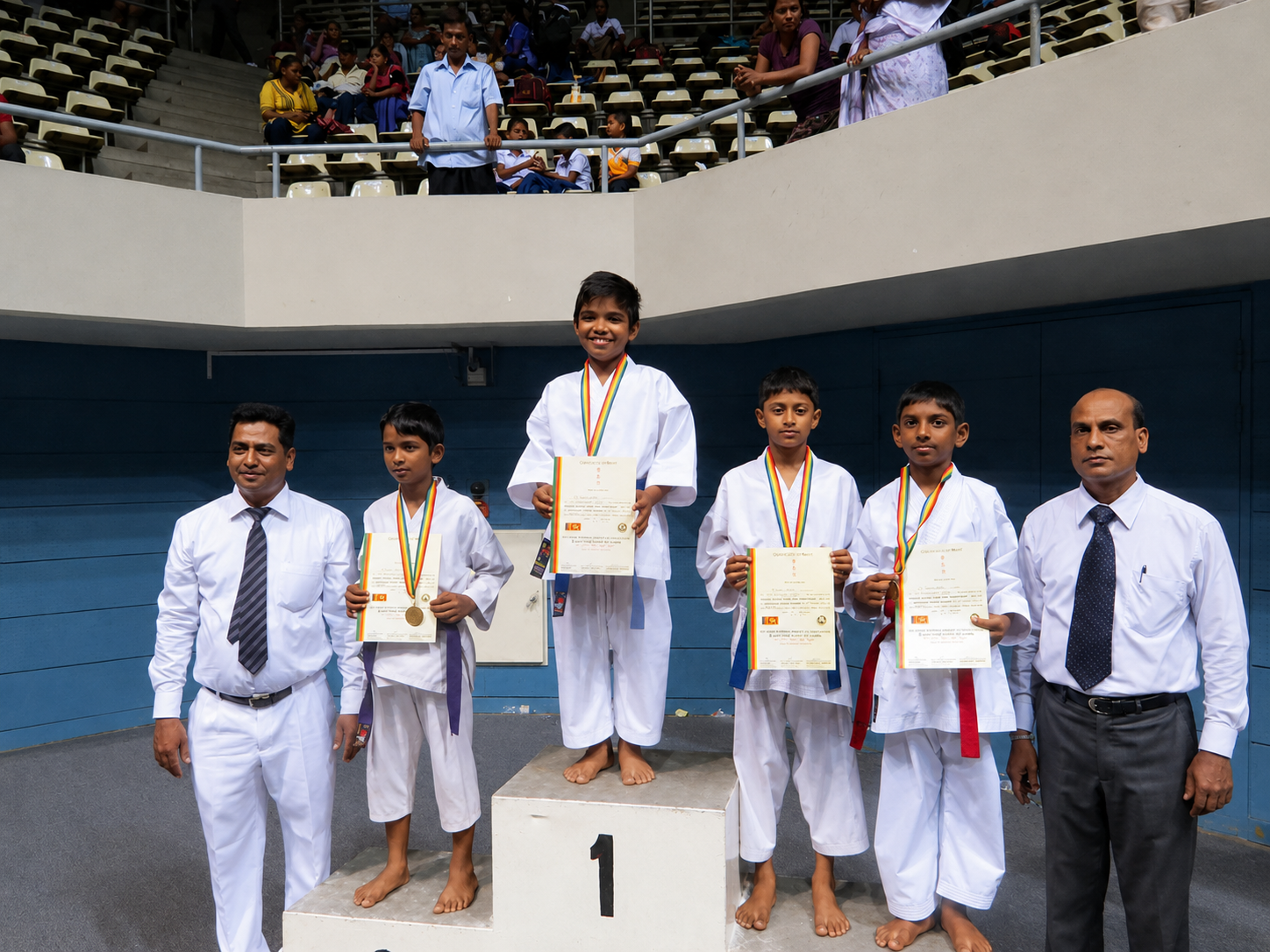Young karate medallists standing on a tournament podium with their coaches