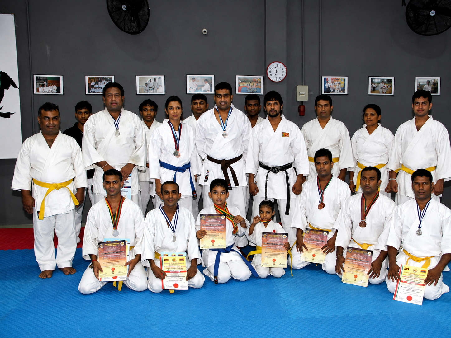 Karate team posing together with tournament medals and certificates