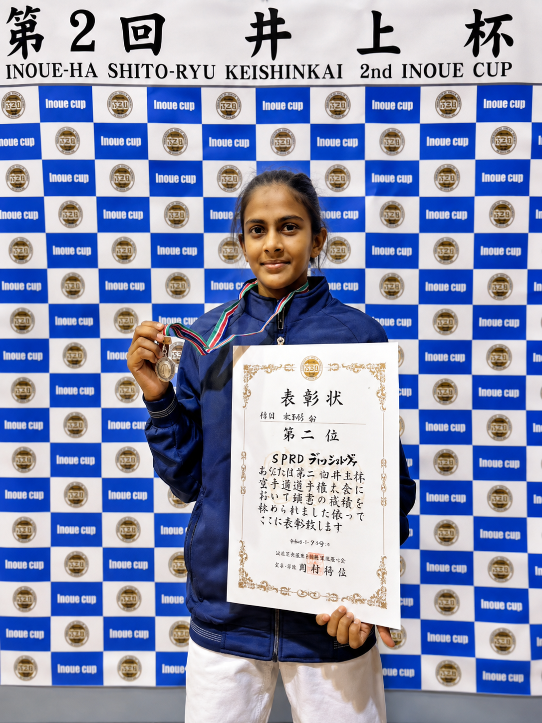 Junior karate athlete holding a silver medal and certificate at the 2nd Inoue Cup